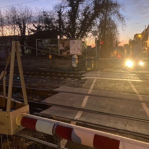 Foto mit Plakat an einem Bahnübergang